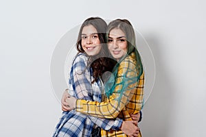 two young girls sisters or friends hug and smile looking at the frame