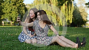 Two young girls sitting on a nature shoot selfies and having fun.