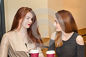 Two young girls talking in a cafeteria
