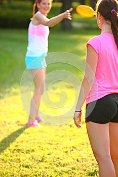 Two young girls are throwing a frisbee