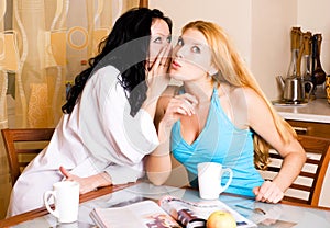 Two young gossiping women in the kitchen