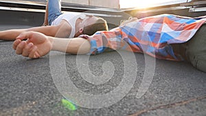 Two young guys lying on roof with bright sunlight at background. Men resting and enjoying life together. Friends