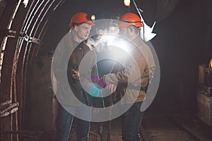 Two young guys in special clothes and helmets standing in the mine