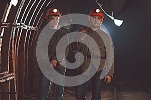 Two young guys in special clothes and helmets standing in the mine