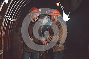 Two young guys in special clothes and helmets standing in the mine