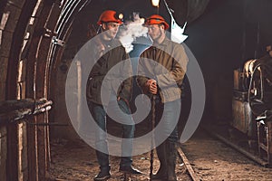 Two young guys in special clothes and helmets standing in the mine