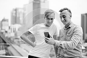 Two young handsome men with blond hair together against view of the city