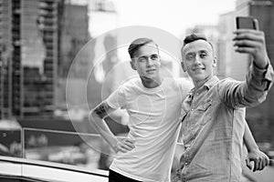 Two young handsome men with blond hair together against view of the city