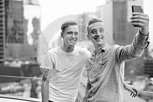 Two young handsome men with blond hair together against view of the city