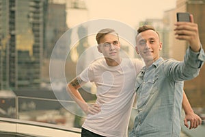 Two young handsome men with blond hair together against view of the city