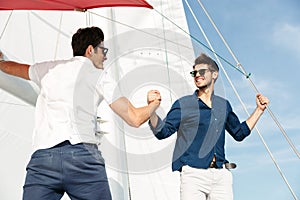 Two young handsome men greeting standing on the yacht