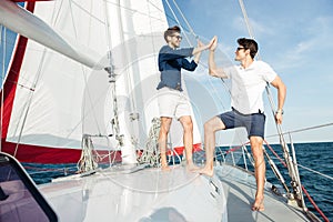 Two young handsome men greeting standing on the yacht