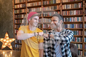 Two young handsome men putting fist to fist and looking happy