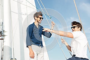Two young handsome men talking while standing on the yacht