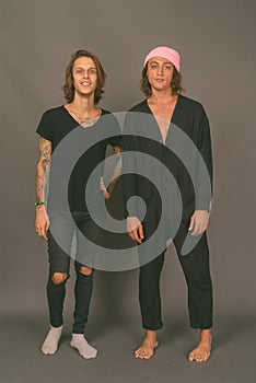 Two young handsome men together against gray background