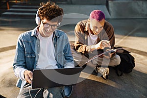 Two young handsome stylish students doing homework together