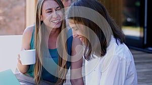 Two young happy beautiful 25-30 year old Caucasian female friends having coffee talking at comfortable cafe terrace.