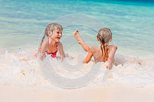 Two young happy children - girl and boy - having fun in water, t