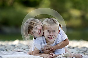 Two young happy cute blond smiling children, boy and girl, broth