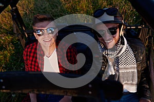 two young happy excited men enjoying beautiful sunny day while driving a off road buggy car