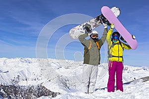 Two young happy friends snowboarders are having fun on ski slope with snowboards in sunny day