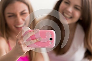 Two young happy girlfriends taking selfie with smart phone.