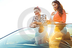 Two young happy girls having fun in the cabriolet outdoors