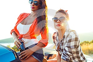 Two young happy girls having fun in the cabriolet outdoors