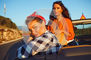 Two young happy girls having fun in the cabriolet outdoors