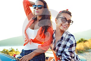 Two young happy girls having fun in the cabriolet outdoors