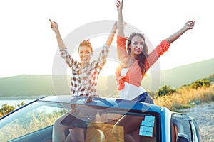 Two young happy girls having fun in the cabriolet outdoors