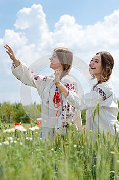 Two young happy girls in traditional ukrainian dress in wheat field