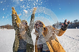 Two young happy people throwing snow and having fun. Selective f