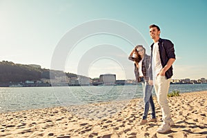Two young happy smiling lovers walking at the beach