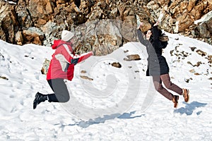 Two young happy teenage girls jumping with pleasure at snow