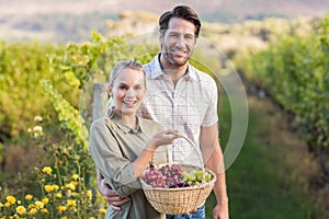 Two young happy vintners holding a basket of grapes photo