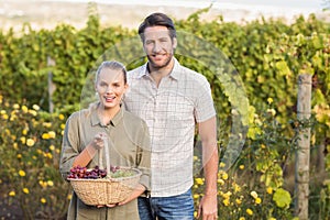 Two young happy vintners holding a basket of grapes photo