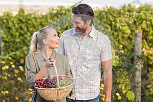 Two young happy vintners holding a basket of grapes photo