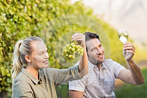 Two young happy vintners holding a glass of wine and grapes photo