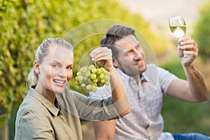 Two young happy vintners holding a glass of wine and grapes photo