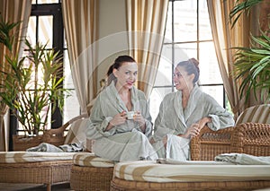 Two young happy women drinking tea at spa resort