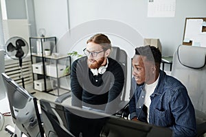Two young intercultural diversity programmers looking at compute screen
