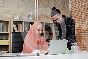 Two young Islamic colleagues work in a small startup office