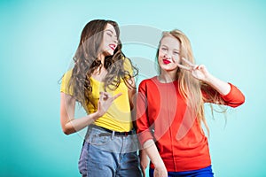 Two young joyful women on blue background. Youth, happiness, fashion, friendshi.