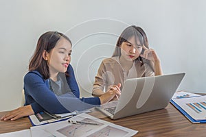 Two young ladies working on laptop and financial paperworks