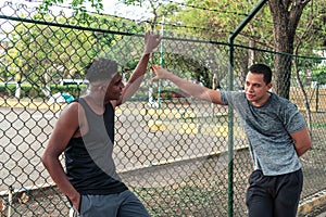 Two young Latinos in sportswear talking in the open air
