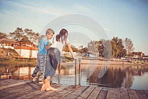 Two young little best friends, boy and girl fishing on a lake in a sunny summer day