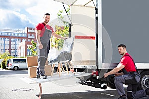 Male Movers Loading Cardboard Boxes In Truck On Street photo