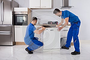 Two Movers Placing Dishwasher In Kitchen