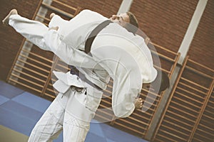 Two young males practicing judo together.